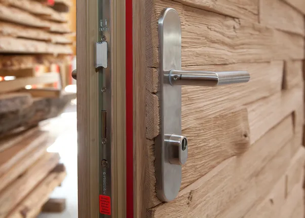 Massivholztür mit moderner Sicherheitsverriegelung und Edelstahlgriff in Schreinerei