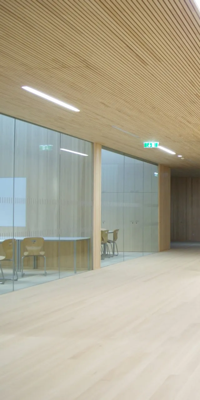 Heller moderner Büroraum mit Glaswänden, Holzverkleidung und Konferenztisch mit Stühlen