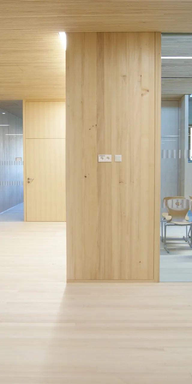 Modernes Büro mit Holzverkleidung, Glastrennwand und Konferenztisch mit Holzstühlen