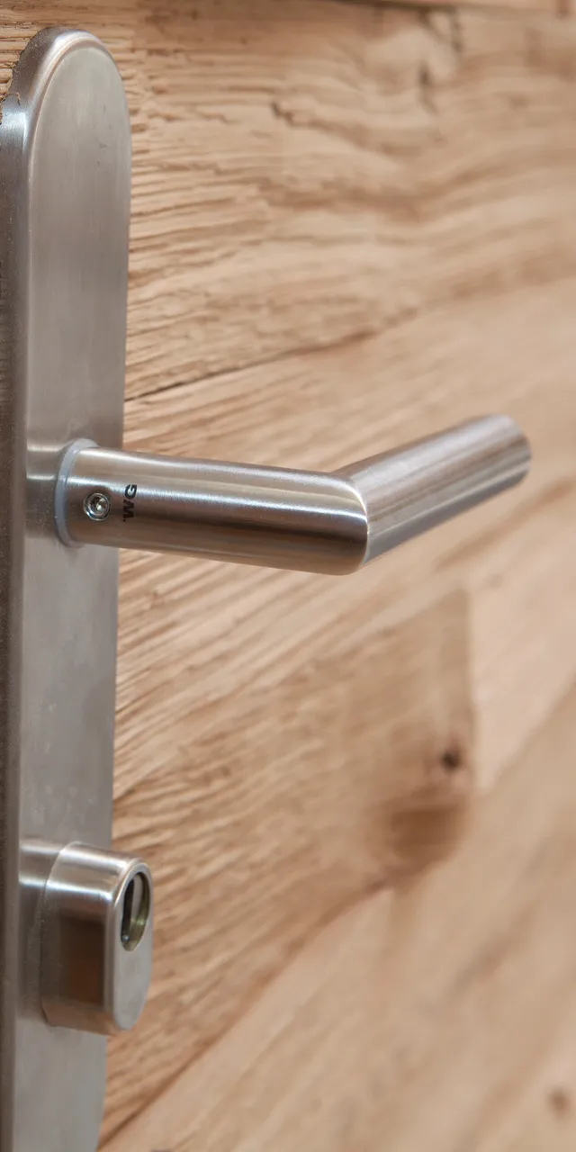 Massivholztür mit Edelstahlgriff und Sicherheitsverriegelung in Nahaufnahme