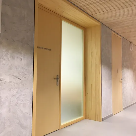Holztür mit der Aufschrift 'KLEIDE MÄDCHEN' in einem modernen Innenflur