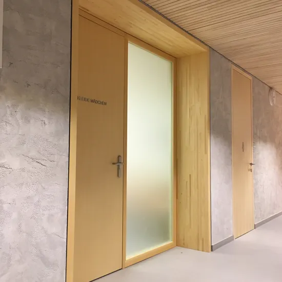 Holztür mit der Aufschrift 'KLEIDE MÄDCHEN' in einem modernen Innenflur