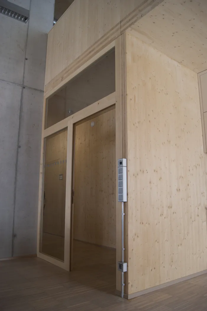 Moderne Holztür mit Glaselementen in einem Bürogebäude mit Sichtbetonwand