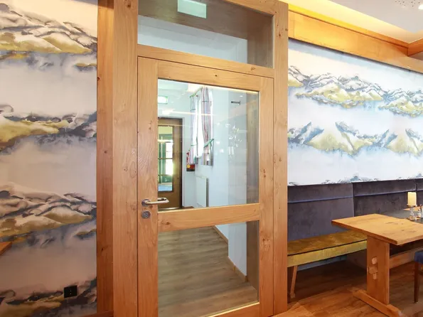 Modernes Restaurant mit Holzboden, bunten Stühlen und Wanddeko mit Bergmotiven