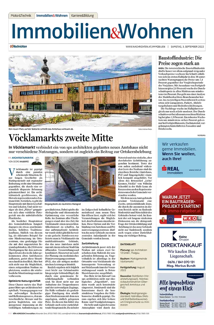 Moderne Außenansicht des neuen Amtshauses in Vöcklamarkt mit Holzfassade und Kirchturm im Hintergrund