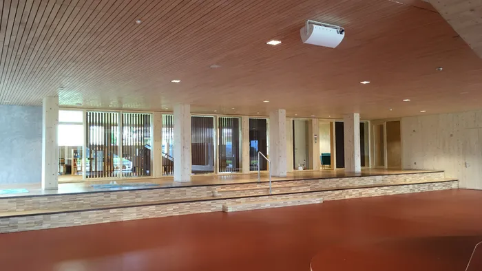 Modernes Innenraumdesign mit Holzdecke, roten Bodenflächen und Glasfront mit vertikalen Lamellen