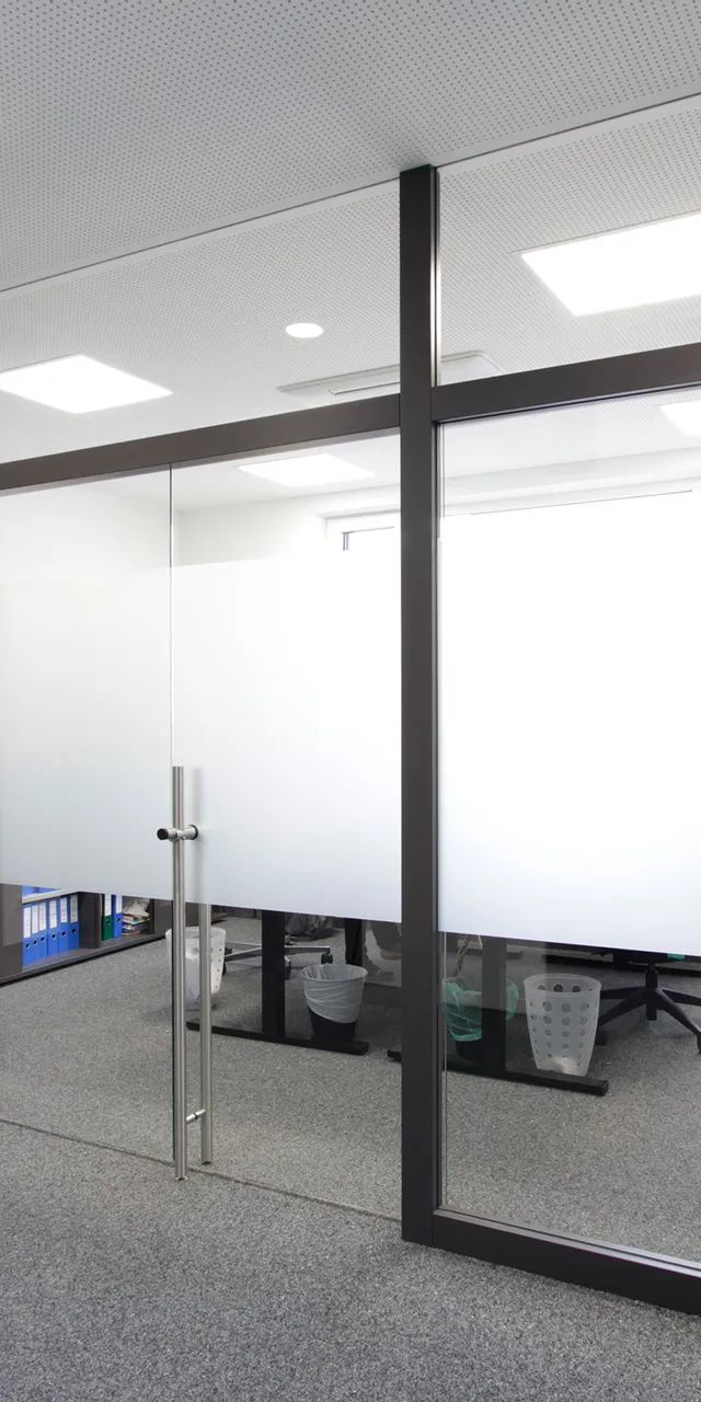 Modernes Büro mit Glastrennwand und grauem Teppichboden