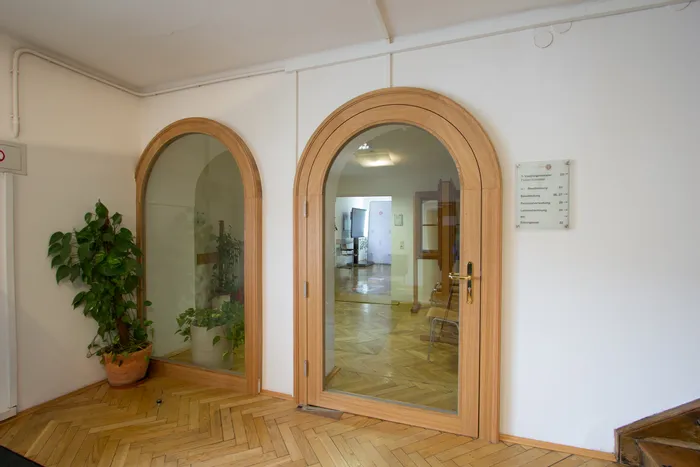 Innenbereich mit Holztür und Glas, Parkettboden und Topfpflanzen im Bürogebäude