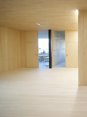 Modernes Büro mit Holzverkleidung, Glastrennwand und Konferenztisch mit Holzstühlen