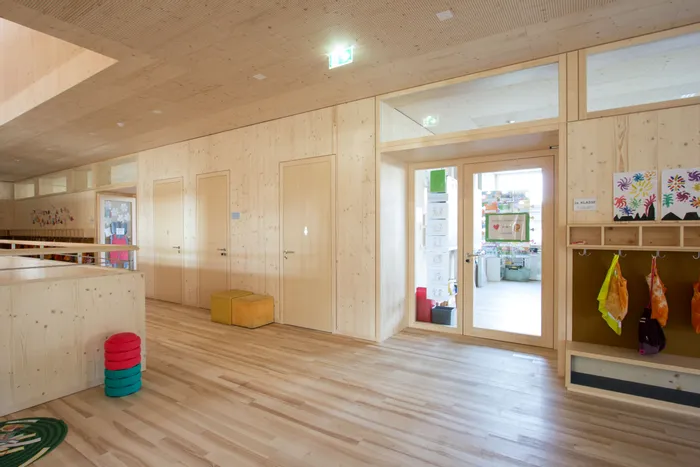 Heller Flur in einer Grundschule mit Holzwänden, Kinderzeichnungen und Garderobe