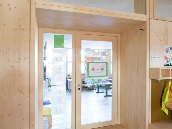 Holztür mit Glasfenstern zu einem farbenfrohen Klassenzimmer der 2A Klasse in einer Grundschule