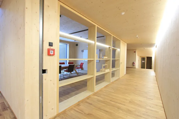 Heller Flur mit Glaswand und Blick in modernen Besprechungsraum mit Holzeinrichtung