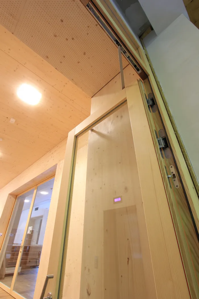 Nahaufnahme einer modernen Glastür mit Holzrahmen in einem Holzgebäude mit automatischem Türschließer