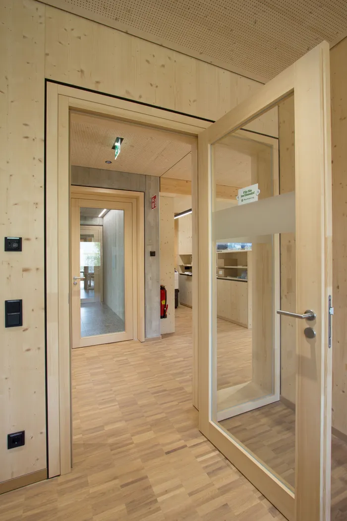 Innenraum eines modernen Gebäudes mit Holztüren, Holzboden und Glaselementen