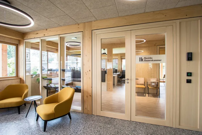 Moderne Wartezone mit gelben Sesseln vor dem Büro der Bezirksbauernkammer mit Glastüren