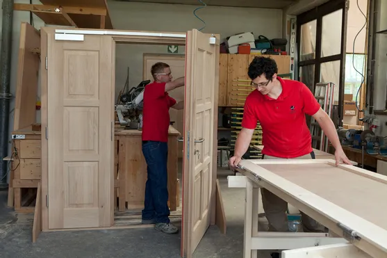 Zwei Tischler montieren Holztüren in einer professionellen Werkstatt