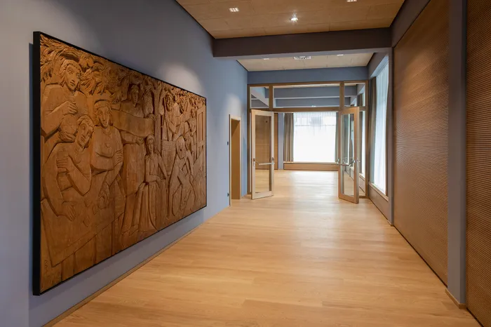 Heller Flur mit Holzskulptur an der Wand und offenem Zugang zu einem lichtdurchfluteten Raum