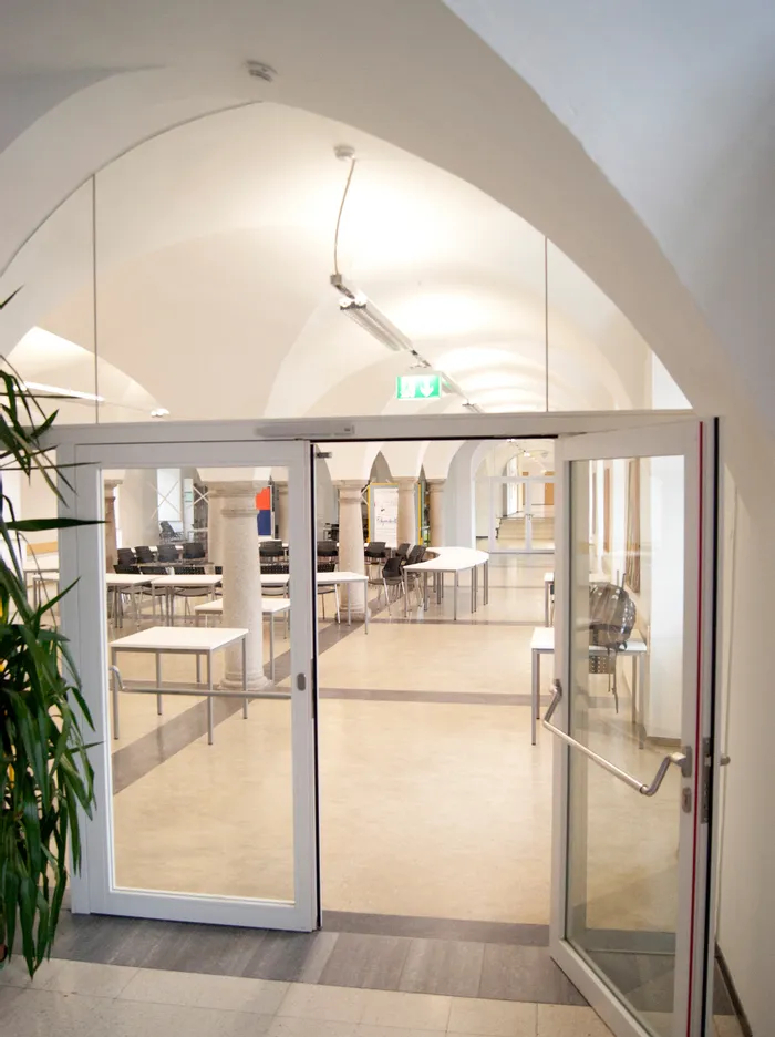 Moderner heller Seminarraum mit Tischen und Stühlen in einem Gebäude mit Gewölbedecke