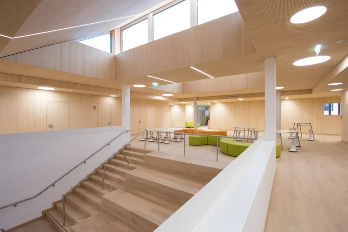 Helle Schul-Lounge mit Holzverkleidung, Sitzgelegenheiten und modernen Möbeln