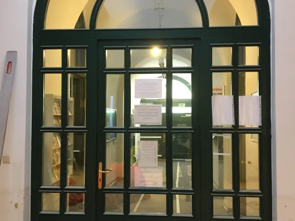 Grüne Doppeltür mit Oberlicht in einem Altbauflur, Zettel mit Informationen angebracht