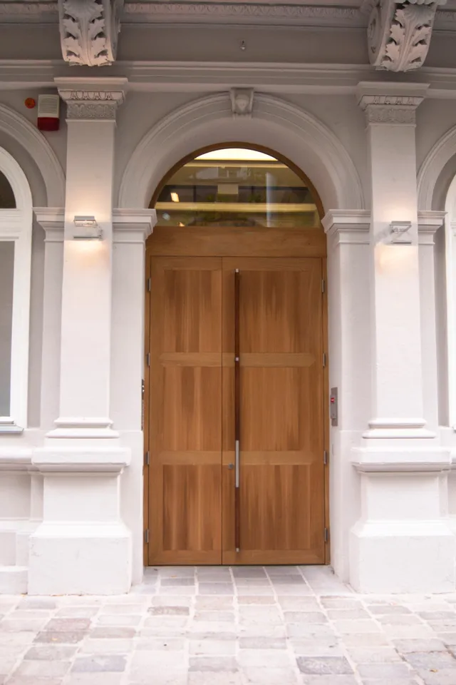 Historische Gebäudevorderseite mit hölzerner Doppeltür und weißen Rundbogenfenstern