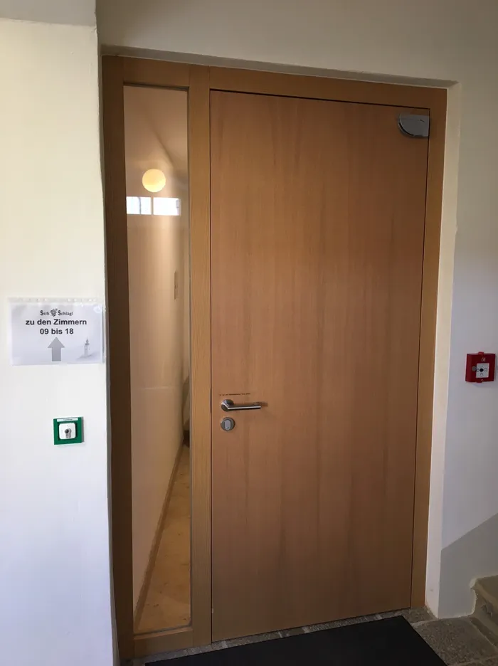 Holztür mit Glaseinsatz in einem Flur mit Hinweis zu den Zimmern 9 bis 18