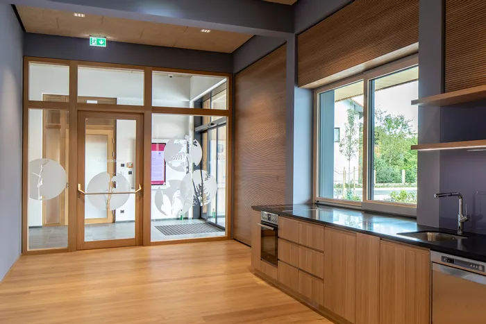 Moderne Holzküche mit schwarzer Arbeitsplatte und Blick auf Eingang mit Glastür