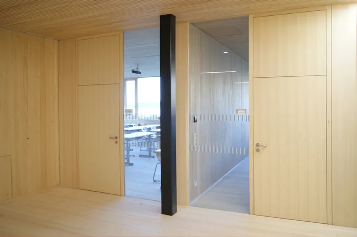 Moderner Klassenraum mit Holzwänden und Glastür in einer Schule