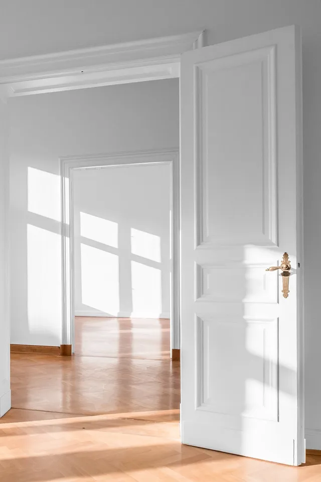 Helle Altbauwohnung mit geöffneten weißen Doppeltüren und Parkettboden im Sonnenlicht