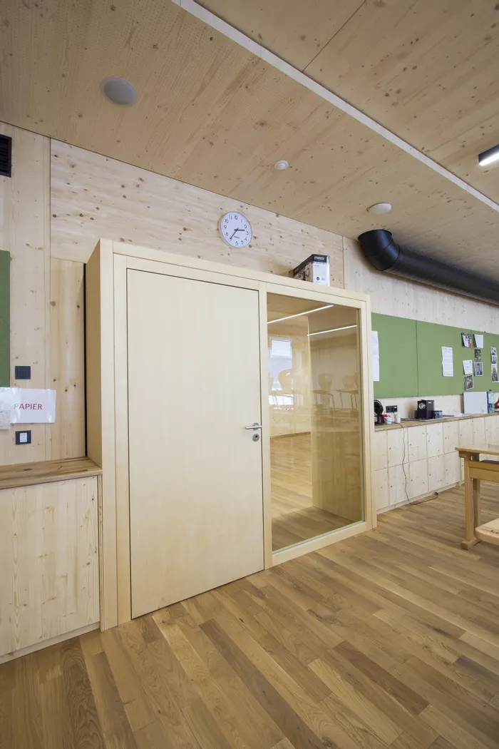 Moderne Holzsprechkabine in einem Büroraum mit Glastür und Uhr an der Wand