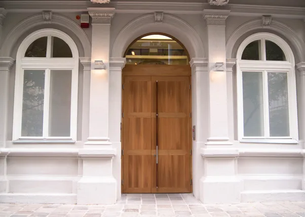 Holztür mit Glasoberlicht in klassischer weißer Fassade mit Bogenfenstern