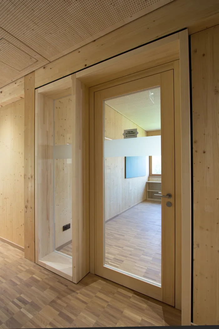 Innenraum mit Holztür und Glaseinsatz in moderner Holzverkleidung