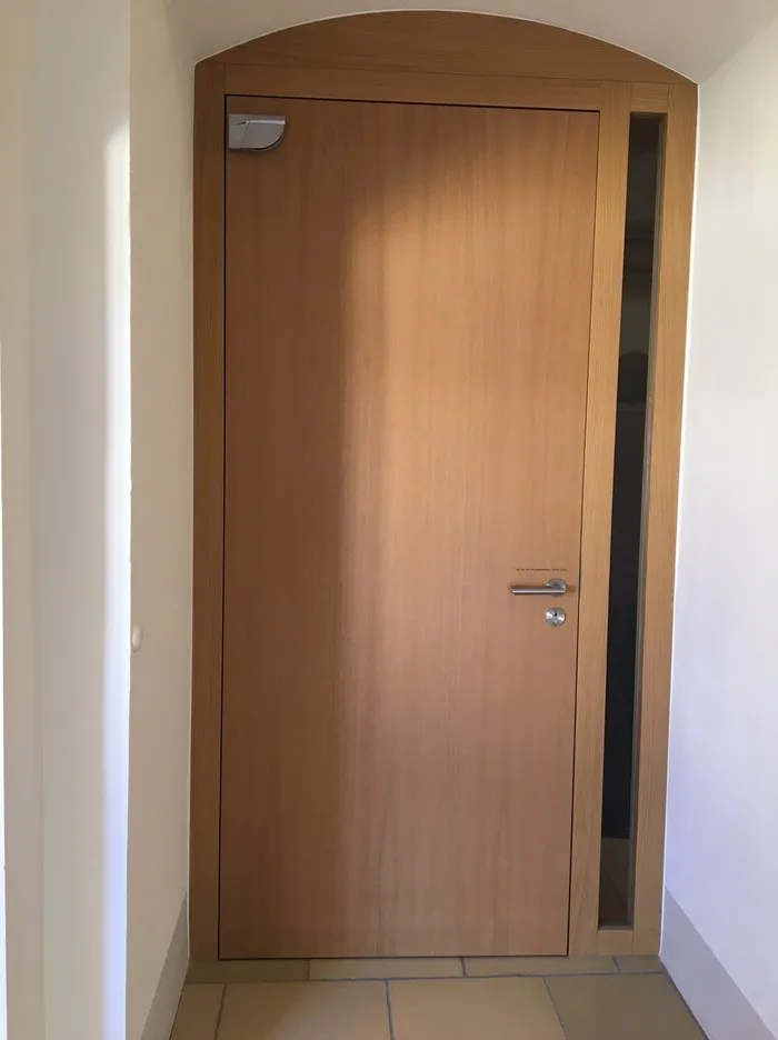 Holztür mit Glaseinsatz und modernem Türgriff in einem hellen Flur