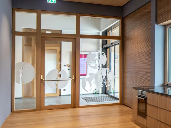 Moderne Holzküche mit schwarzer Arbeitsplatte und Blick auf Eingang mit Glastür