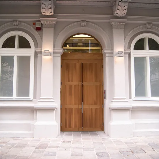 Holztür mit Glasoberlicht in klassischer weißer Fassade mit Bogenfenstern