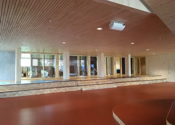 Modernes Innenraumdesign mit Holzdecke, roten Bodenflächen und Glasfront mit vertikalen Lamellen