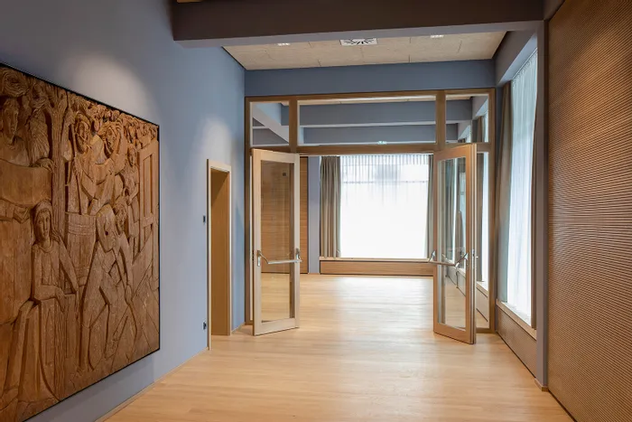 Moderner Innenraum mit Holzskulptur, Glastüren und natürlichem Licht durch große Fenster