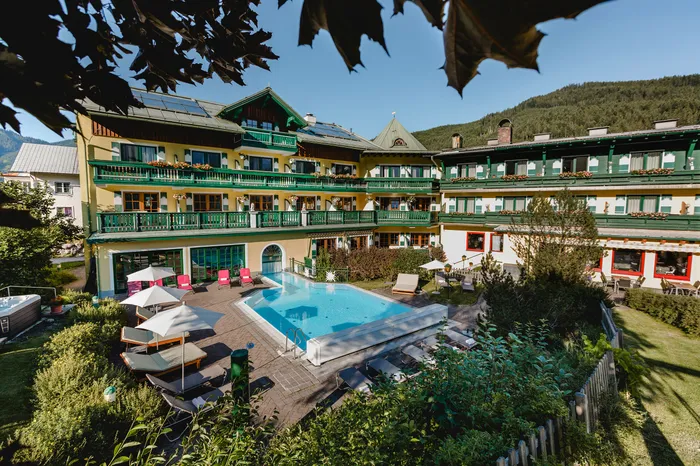 Traditionelles Hotel mit Balkon und Außenpool in Alpenlage bei sonnigem Wetter
