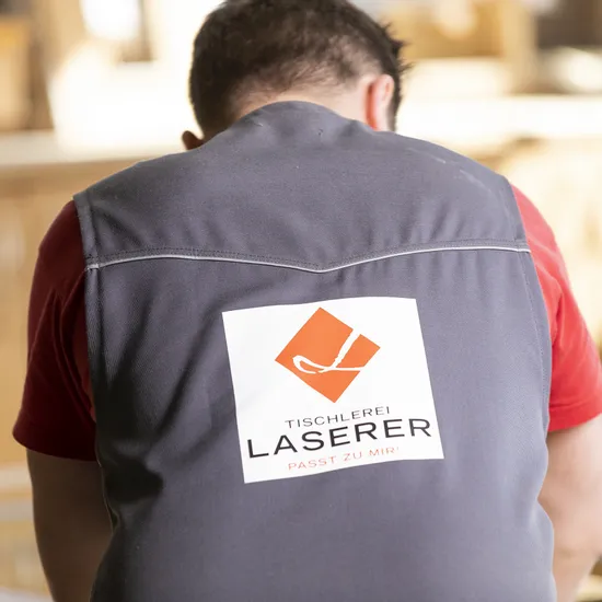 Rückansicht eines Tischlers mit Logo der Tischlerei Laserer auf seiner Arbeitskleidung
