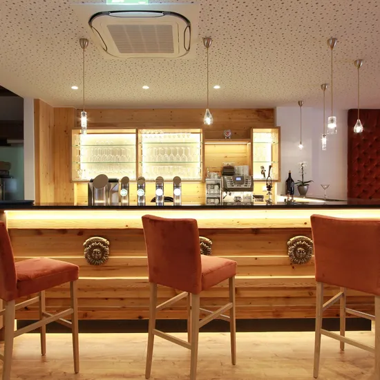 Moderne Hotelbar mit Holztheke, Barhockern und stilvoller Beleuchtung