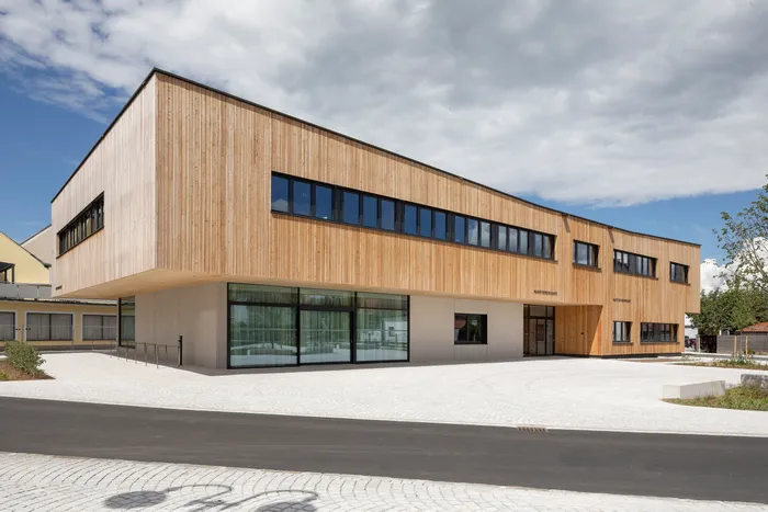 Modernes Gemeindezentrum mit Holzfassade und großen Fenstern bei Tageslicht