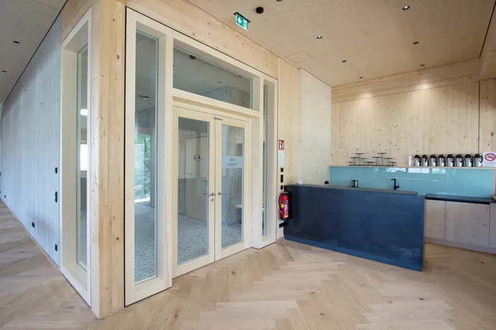 Moderner Empfangsbereich mit Holzwänden, Glastüren und schwarzem Tresen