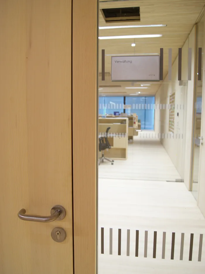 Bürotür mit Schild Verwaltung, Blick in modernen Verwaltungsraum mit Schreibtischen und Stühlen
