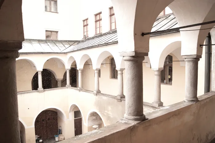 Innenhof mit Arkadengängen und Steinsäulen bei Schneefall in einem historischen Gebäude