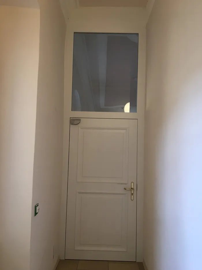 Weiße Innentür mit Glaseinsatz oben in einem schmalen Flur mit beigen Wänden