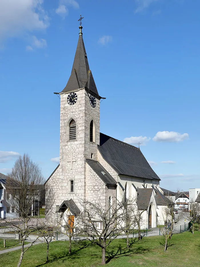 Historische Kirche mit Uhrenturm und spitzem Dach an einem sonnigen Tag