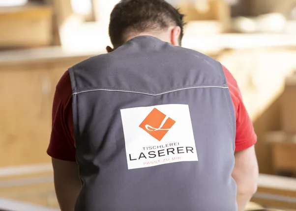 Rückansicht eines Tischlers mit Logo der Tischlerei Laserer auf seiner Arbeitskleidung