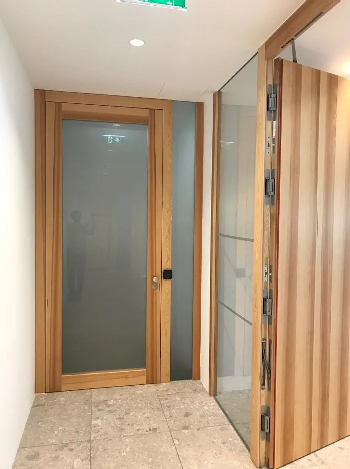 Modernes Holztürsystem mit Glaseinsatz und automatischer Schiebetür in einem Bürogebäude